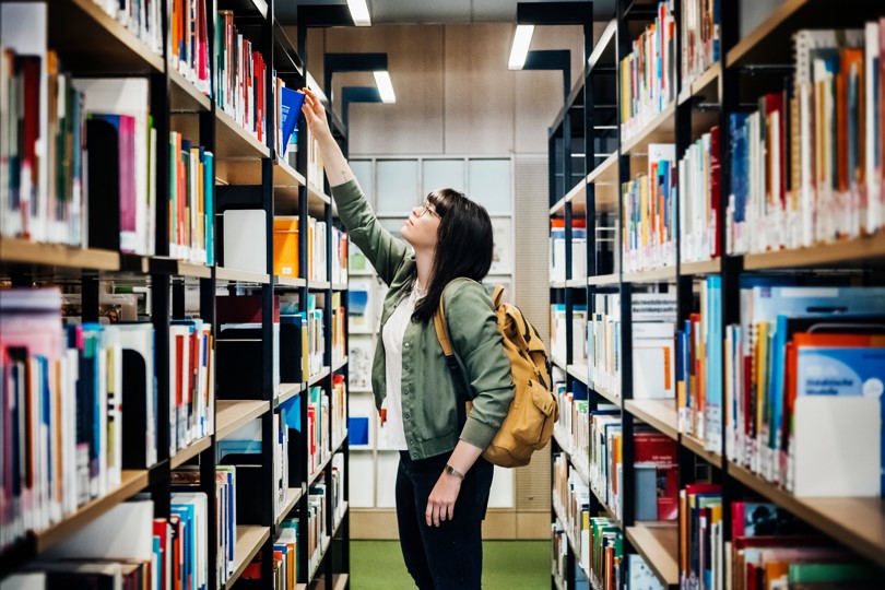 Student in a library searching for a book